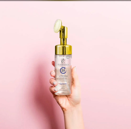 Model holding Inner-Cells Lava Foam Cleanser with gold brush head on pink background