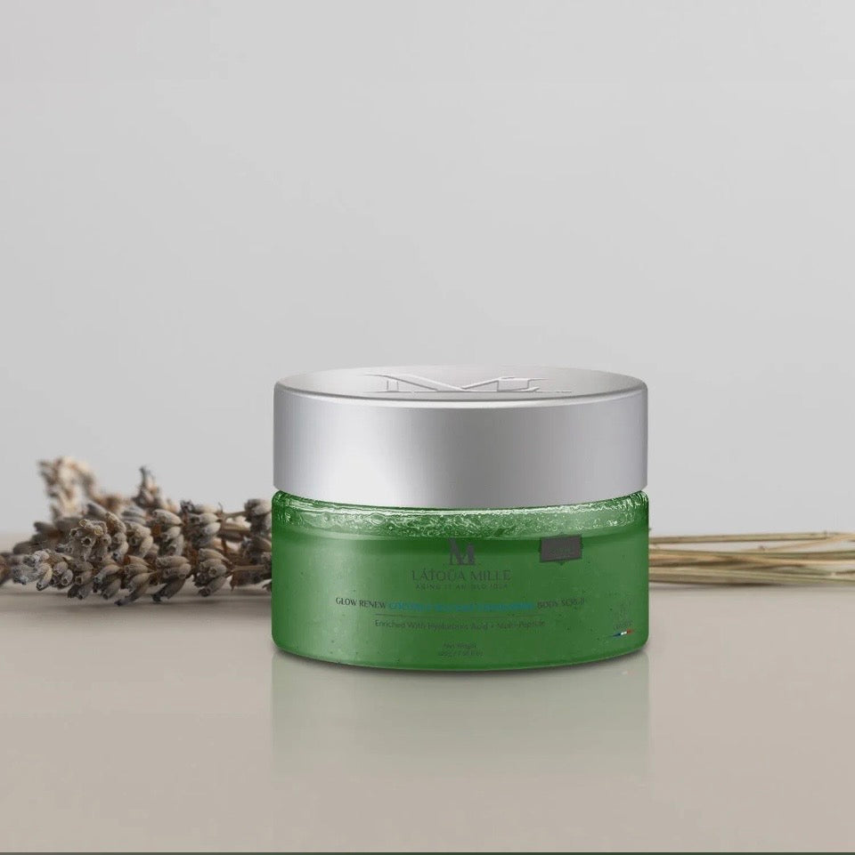 Naéa Millé Glow Renew Body Scrub - emerald green jar with dried lavender lifestyle shot on neutral background